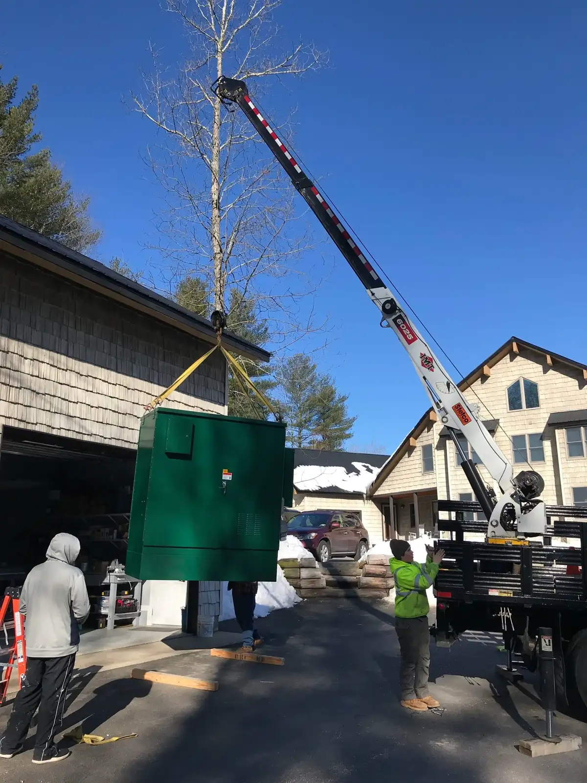 Crane lifting outdoor control cabinet into place at job site